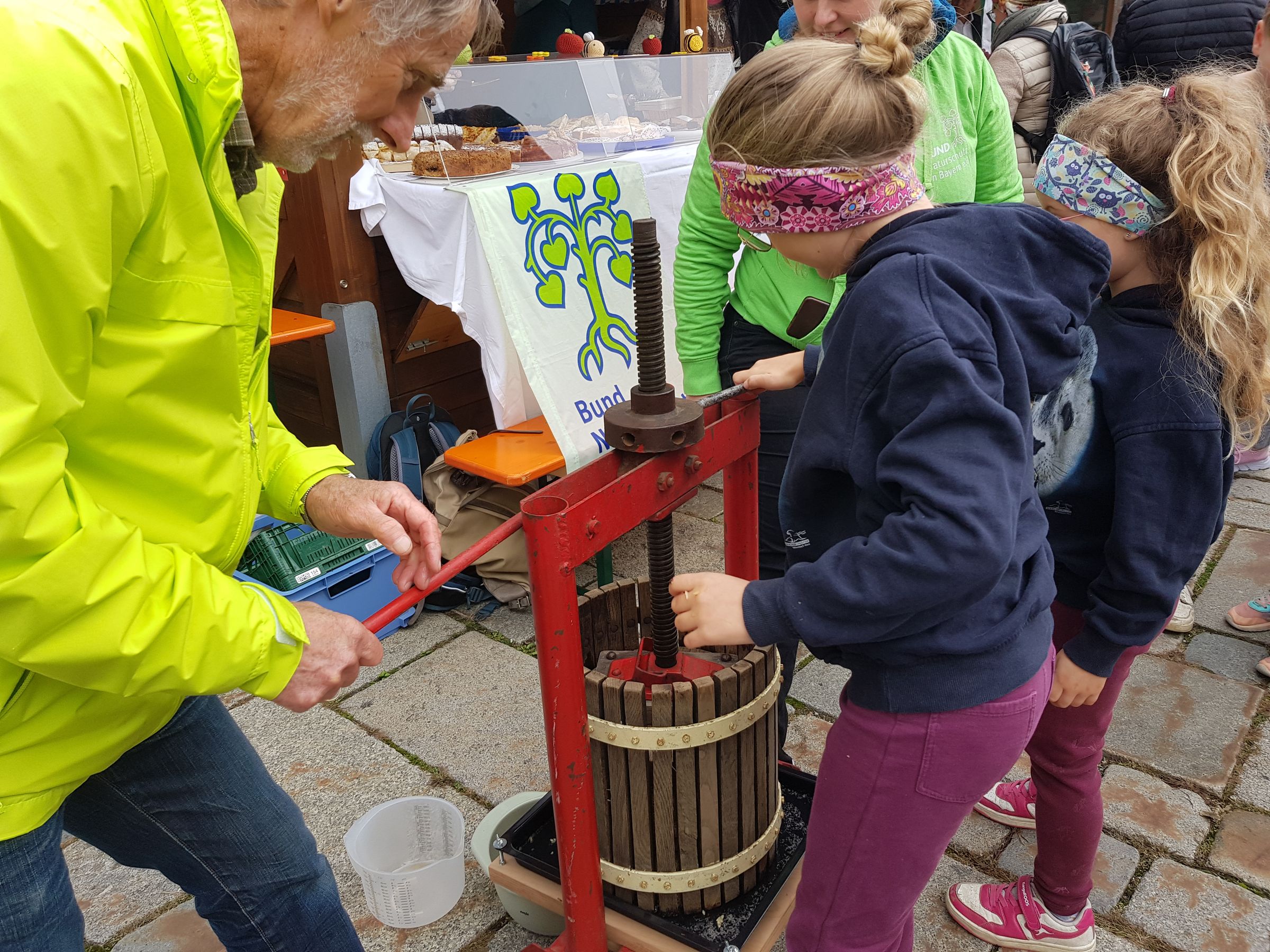 Foto: B. Rutkowski - Apfelmarkt 2025 Kind presst zusammen mit einem Helfer des BN Apfelsaft an einer Kelter