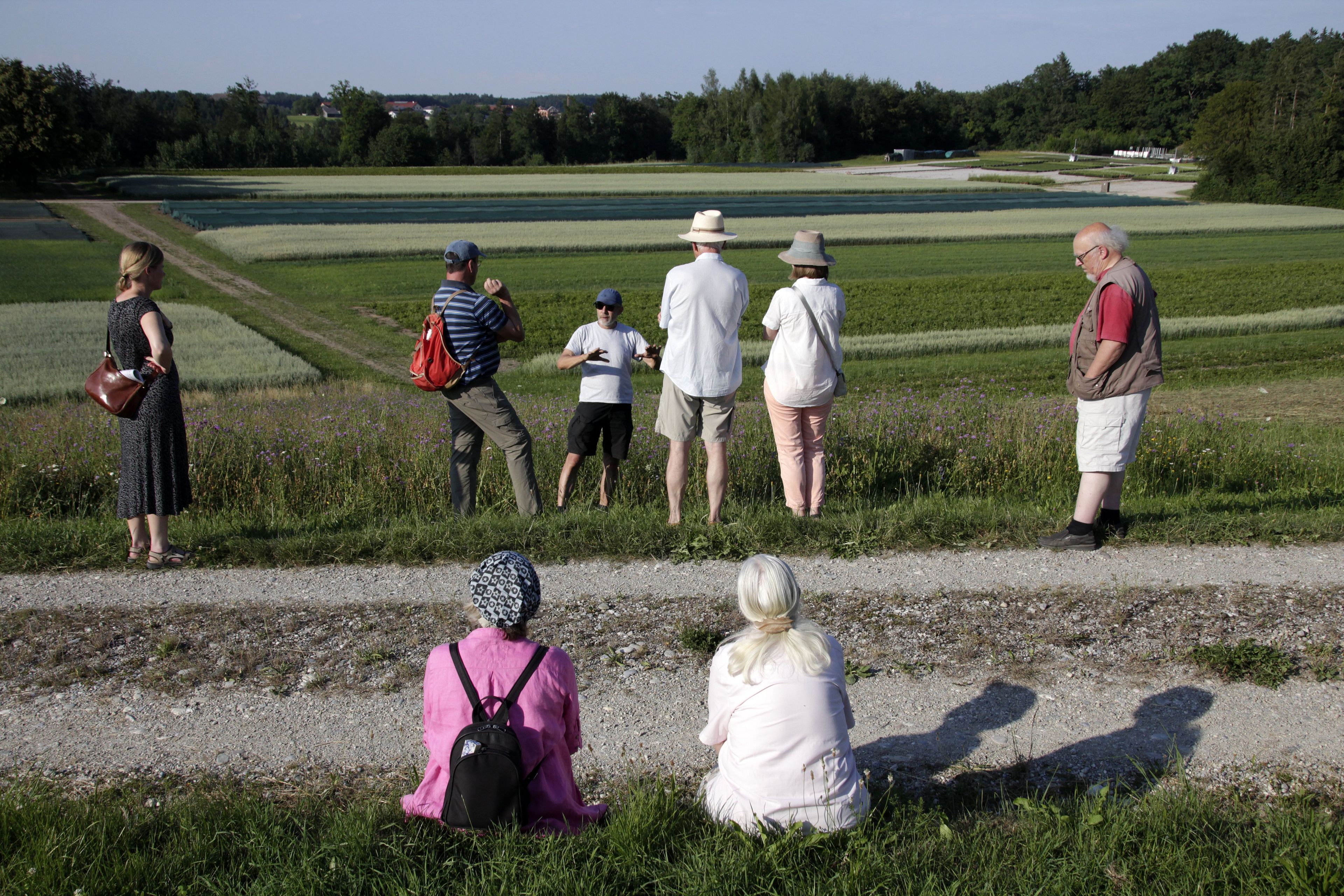 Foto: Claudia Lahr - Exkursion in den Pflanzgarten 24.06.26 Personen sehen sich den Pflanzgarten an und lauschen einem Vortragenden